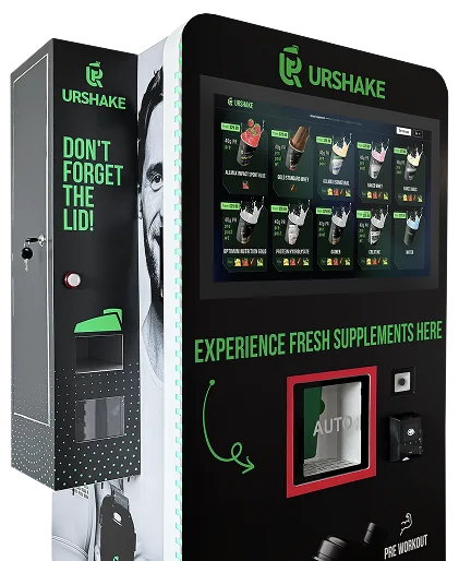A URShake protein vending kiosk installed in a gym, showing its shake menu on the touchscreen with the cup-lid dispenser alongside